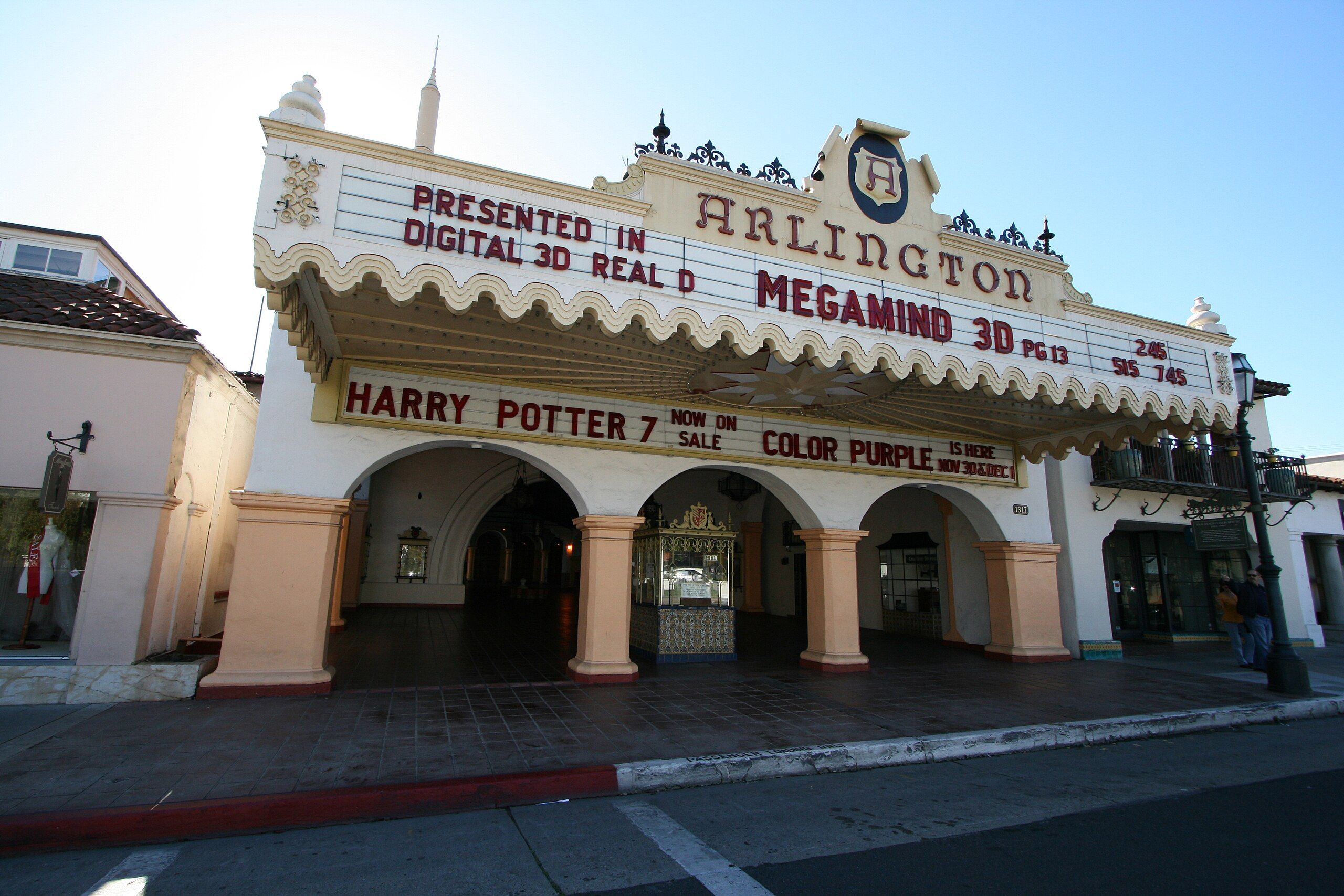 The facade and markee of the Arlington Theater in Santa Barbara, with its three-arched entryway and blue sky overhead.
